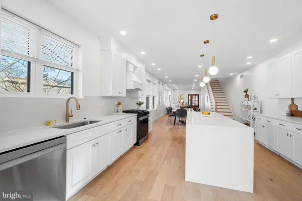 a large white kitchen with a stove a sink a refrigerator and a dining table with wooden floor