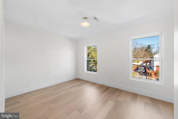 a view of an empty room with window and wooden floor