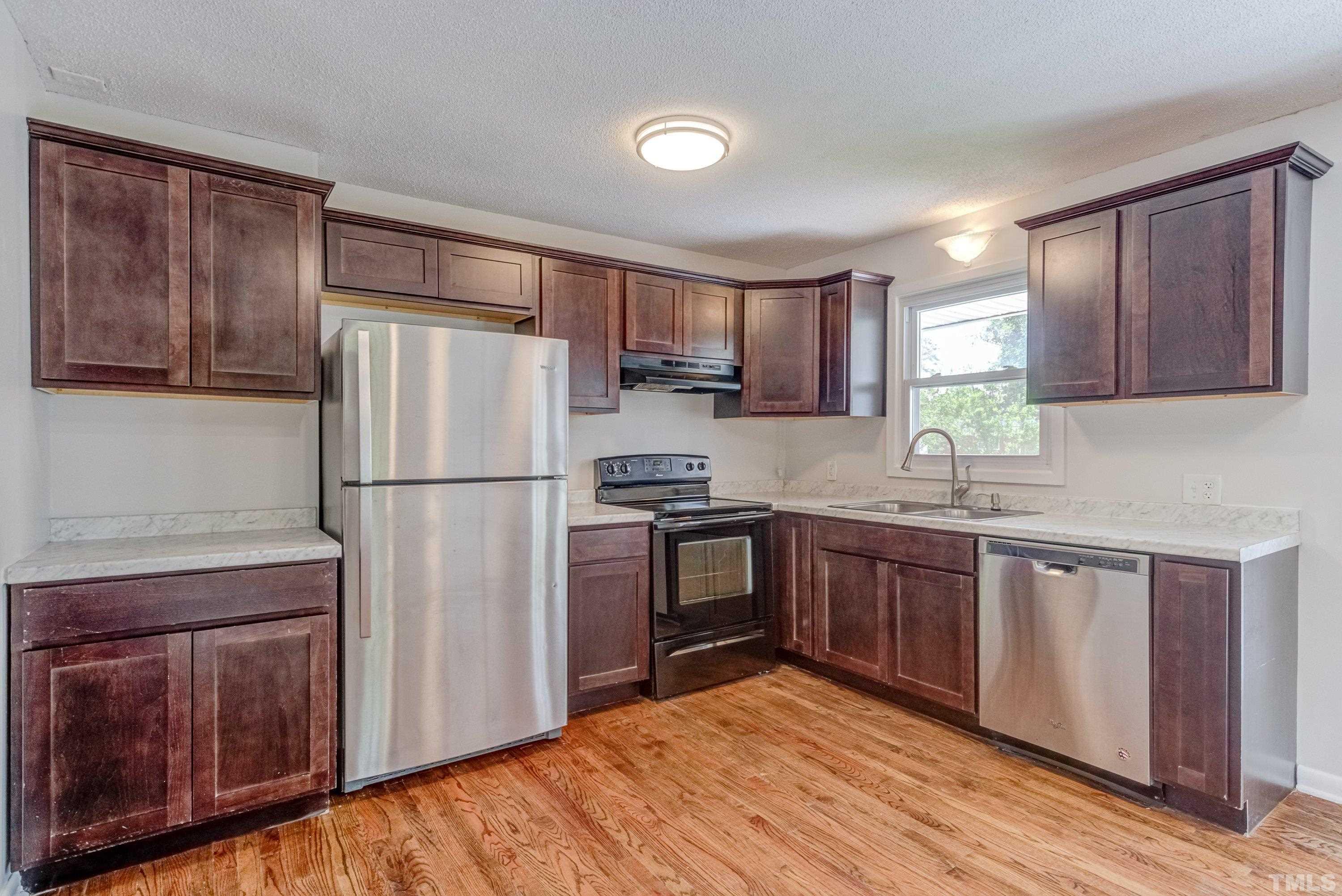3840 Marsh Creek Road Raleigh, NC 27604 - Photo 15 of 41 a kitchen with a refrigerator sink and wooden cabinets