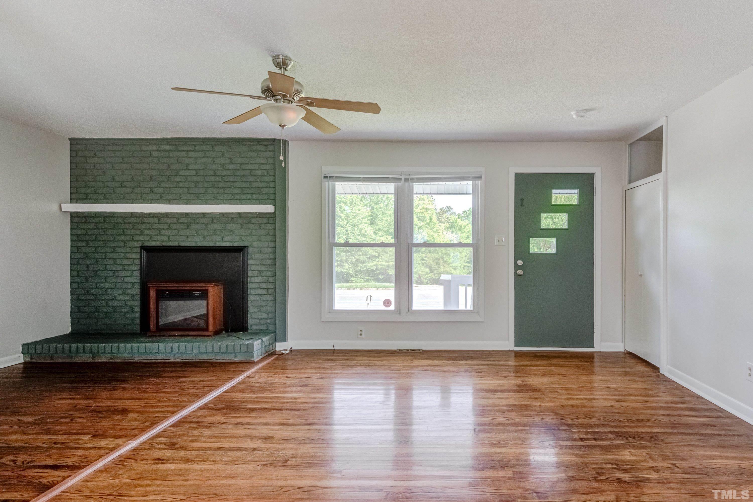 3840 Marsh Creek Road Raleigh, NC 27604 - Photo 7 of 41 a view of an empty room with wooden floor fireplace and a window