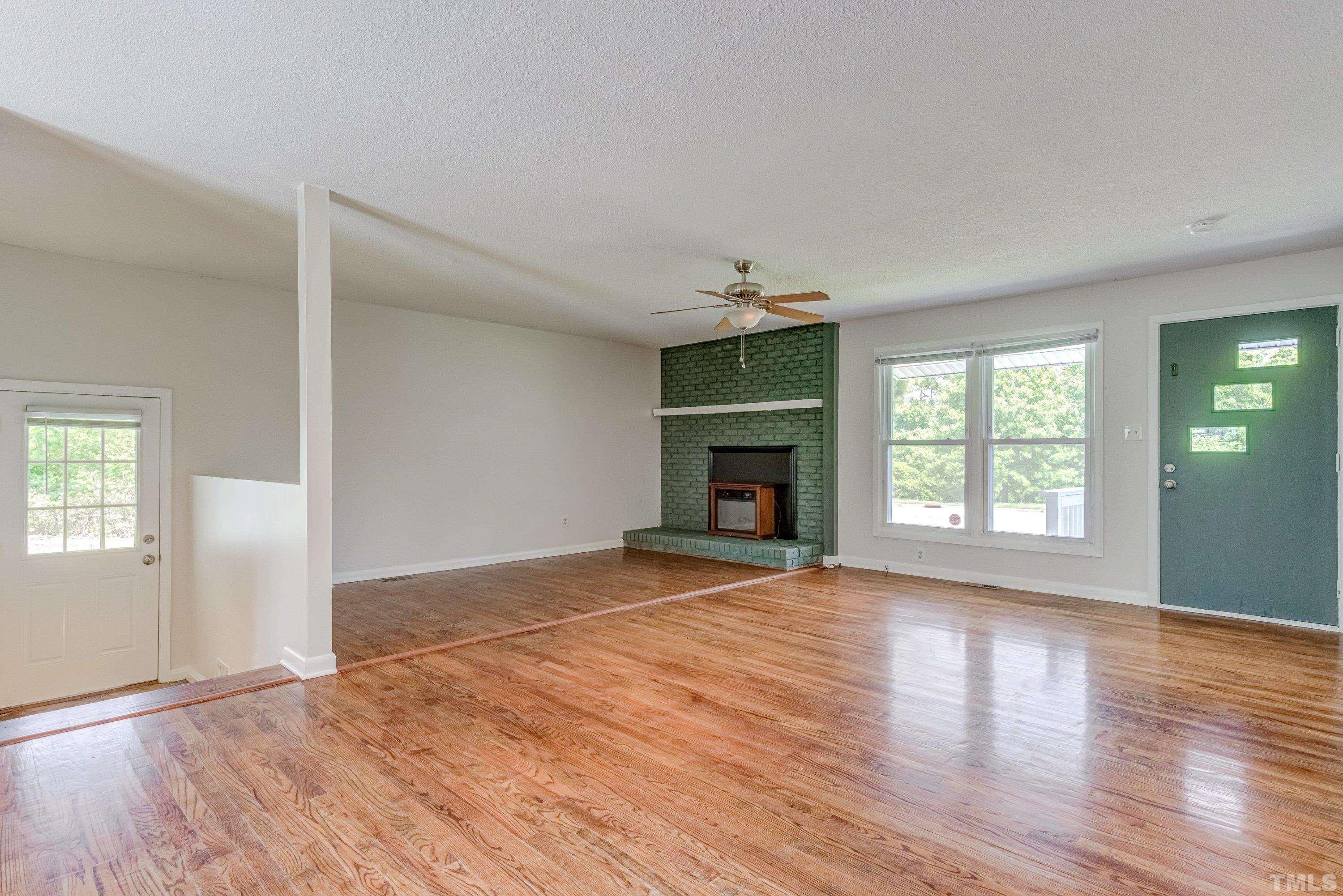 3840 Marsh Creek Road Raleigh, NC 27604 - Photo 9 of 41 an empty room with wooden floor fireplace and windows