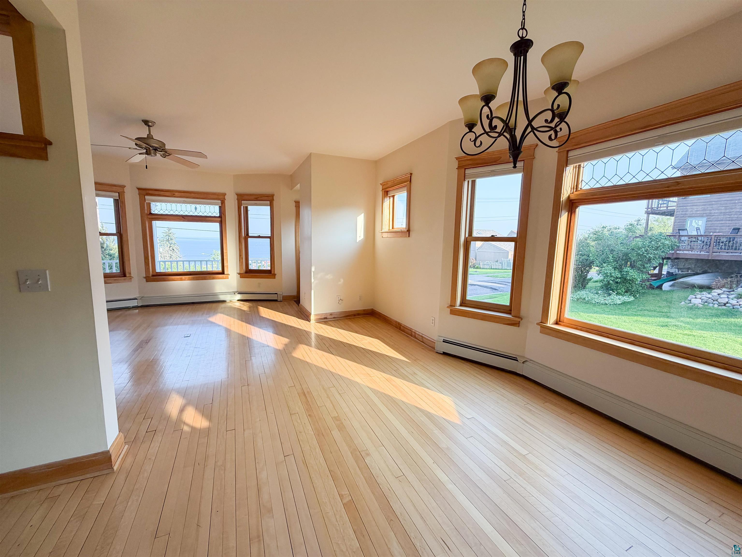 13 West 8th Street Duluth, MN 55806 - Photo 6 of 57 Hardwood flooring throughout featuring bay windows, natural wood trim, a ceiling fan, and a chandelier