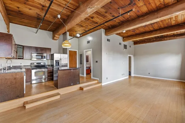 a view of a kitchen with stainless steel appliances granite countertop a stove a refrigerator a sink and dishwasher with wooden floor