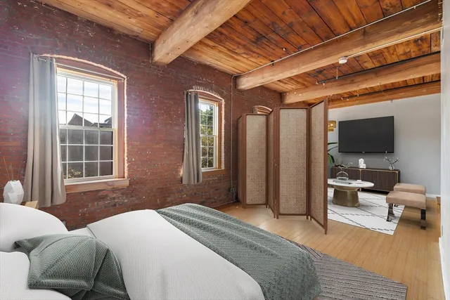 a bedroom with a bed a window and flat screen tv