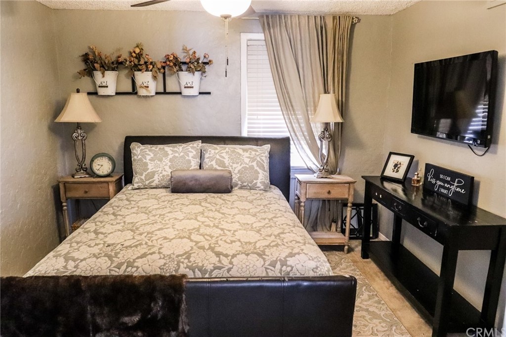 304 C Street Needles, CA 92363 - Photo 37 of 57 a bed sitting in a bedroom next to a window with a flat screen tv and a couch