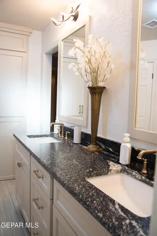 a bathroom with a granite countertop sink and a mirror
