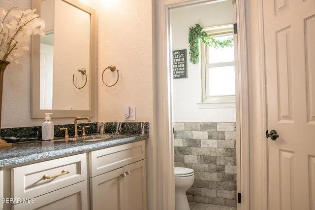 a bathroom with a granite countertop sink a toilet and a mirror