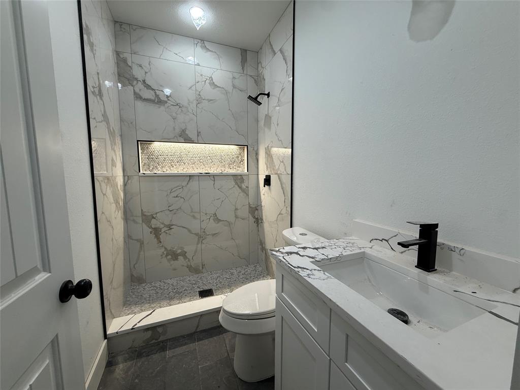 5803 Plum Dale Road Dallas, TX 75241 - Photo 11 of 14 a bathroom with a granite countertop sink a toilet and shower