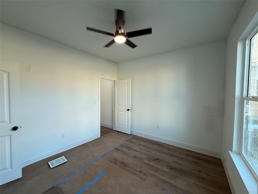 5803 Plum Dale Road Dallas, TX 75241 - Photo 7 of 14 an empty room with wooden floor fan and windows