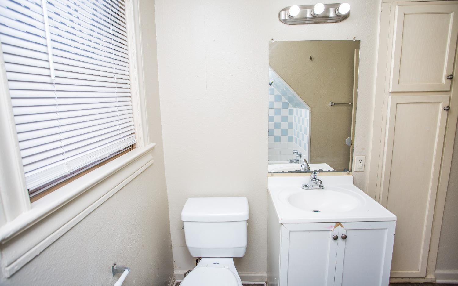 2103 22nd Street Lubbock, TX 79411 - Photo 12 of 18 a bathroom with a sink and mirror with toilet