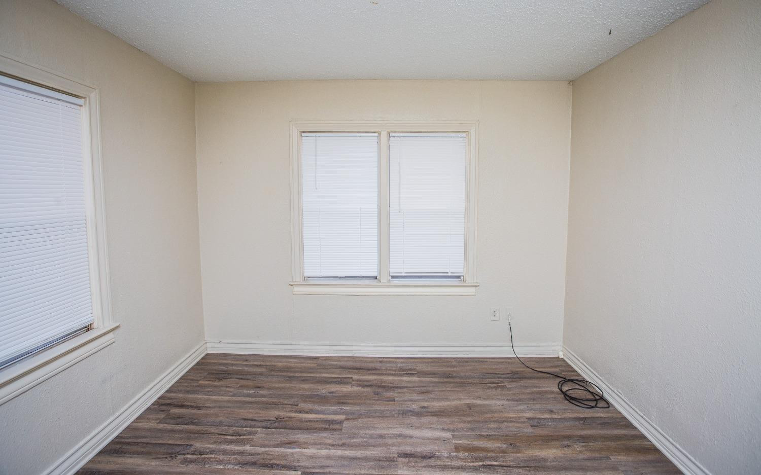 2103 22nd Street Lubbock, TX 79411 - Photo 13 of 18 a view of an empty room with wooden floor and a window