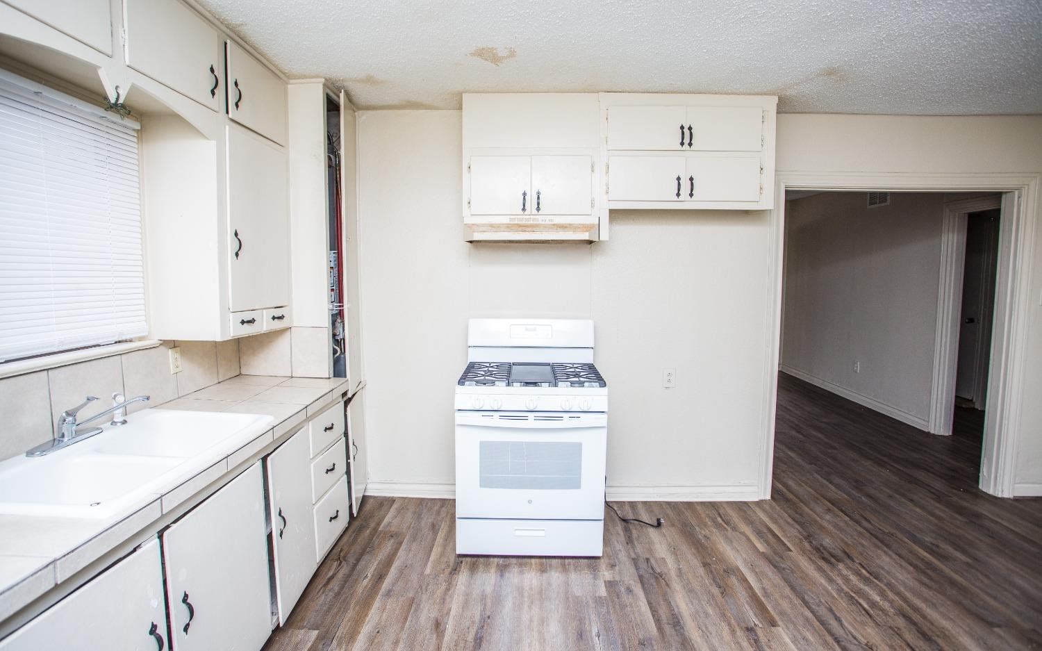 2103 22nd Street Lubbock, TX 79411 - Photo 2 of 18 a kitchen with wooden floors and white appliances