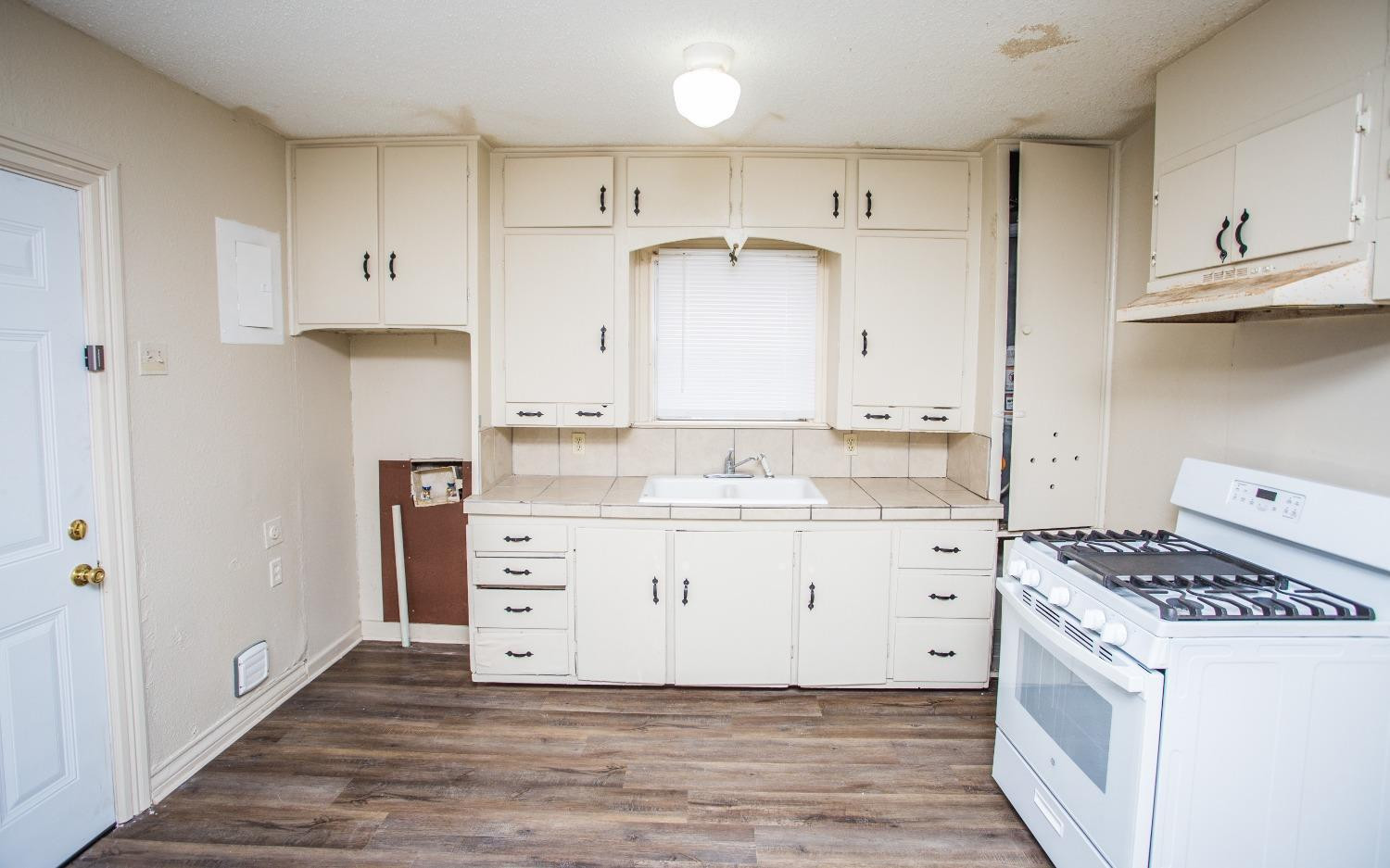 2103 22nd Street Lubbock, TX 79411 - Photo 4 of 18 a kitchen with granite countertop a white stove a sink and cabinets
