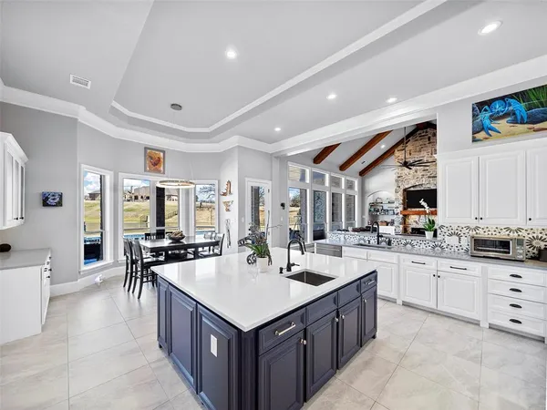 a large kitchen with kitchen island a sink white cabinets and stainless steel appliances