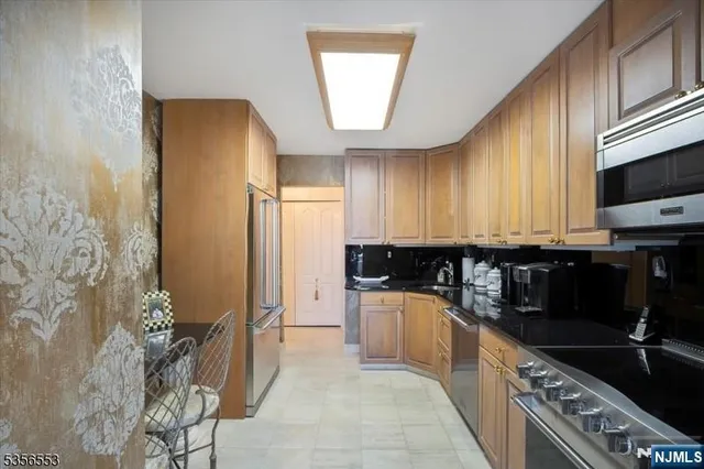 a kitchen with granite countertop a refrigerator a stove a sink dishwasher and wooden cabinets with wooden floor