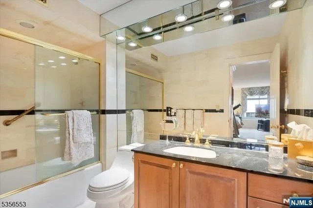 a bathroom with a granite countertop sink a toilet a mirror and shower