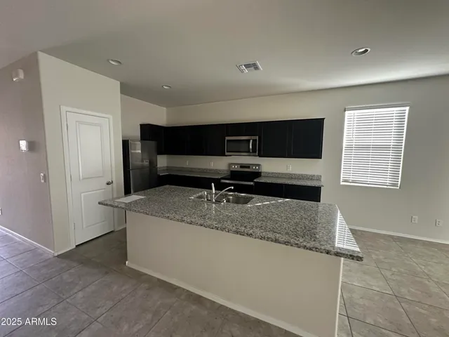 a living room with stainless steel appliances kitchen island granite countertop a refrigerator and a sink