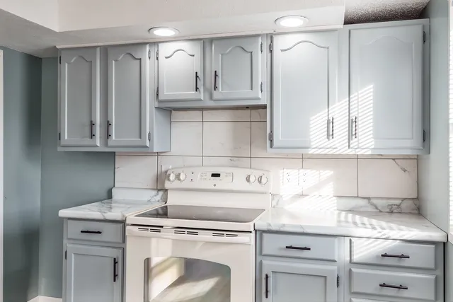 a kitchen with granite countertop white cabinets and white appliances