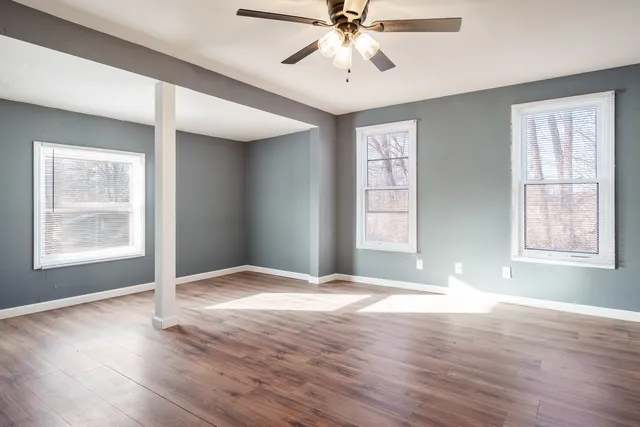 a view of an empty room with wooden floor and window