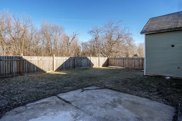 a view of a backyard with large trees and wooden fence