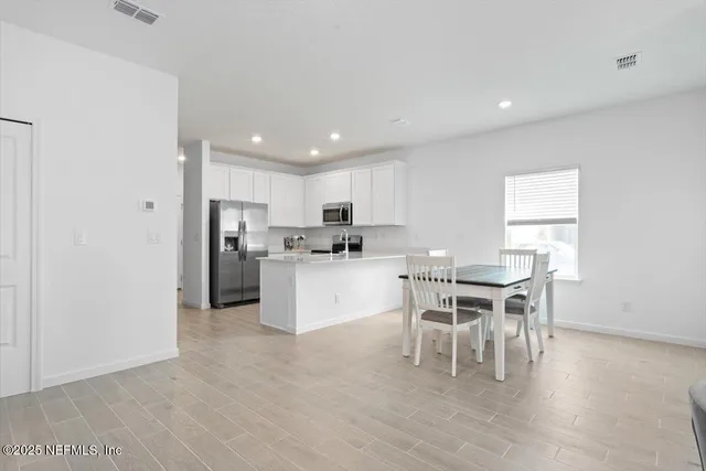 a kitchen with a dining table chairs appliances and cabinets