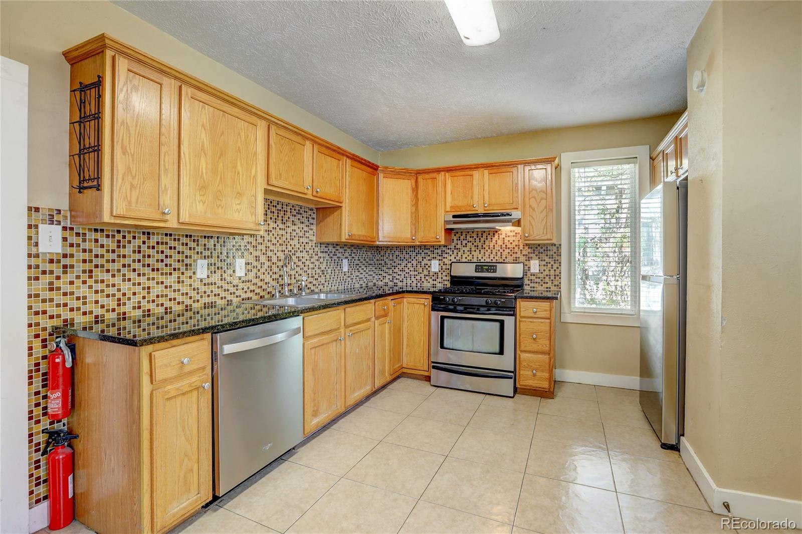 418 Inca Street Denver, CO 80204 - Photo 5 of 24 a kitchen with granite countertop a stove sink and cabinets