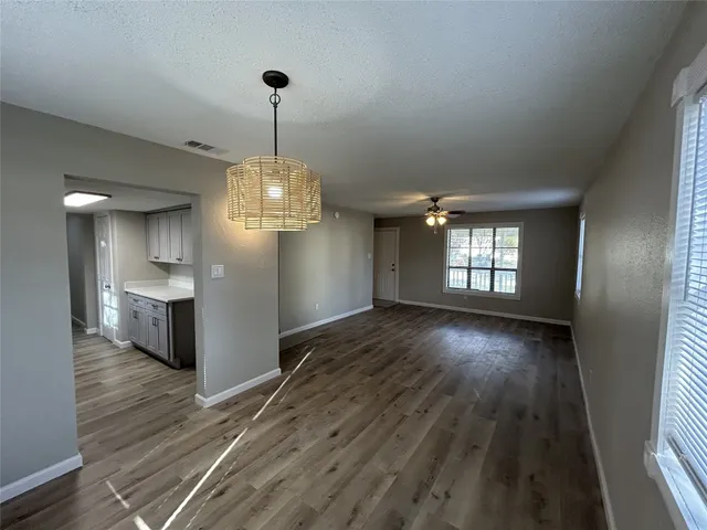 an empty room with a chandelier fan and windows