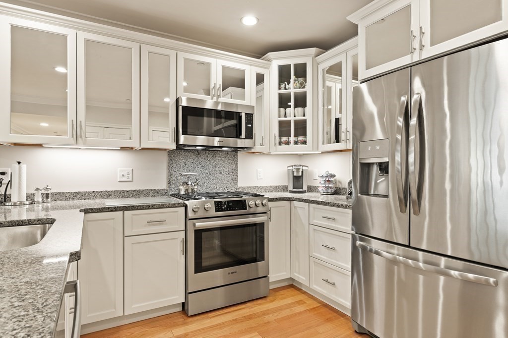 2 Manor Terrace, Unit 209 Lexington, MA 02420 - Photo 14 of 26 a kitchen with stainless steel appliances granite countertop a refrigerator stove and white cabinets