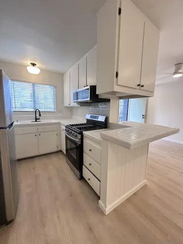 a kitchen with stainless steel appliances granite countertop a sink a stove a refrigerator and white cabinets