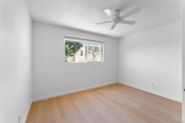 an empty room with a chandelier fan and windows