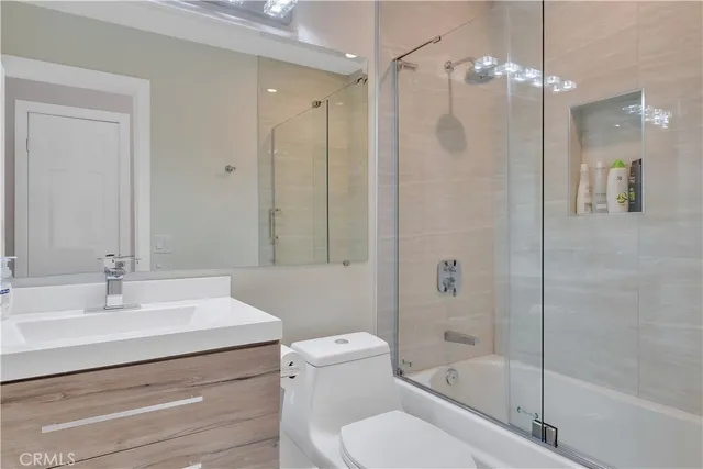 a bathroom with a sink a mirror a toilet and shower