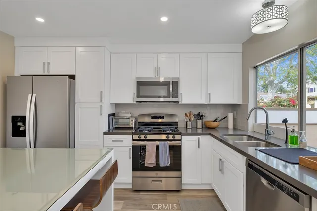 a kitchen with granite countertop a stove a sink and a refrigerator
