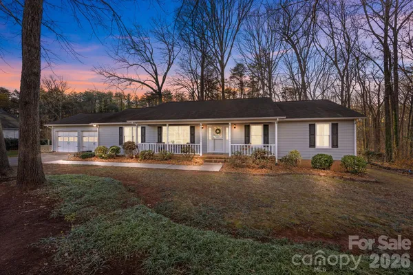 a backyard of a house with table and chairs under an umbrella