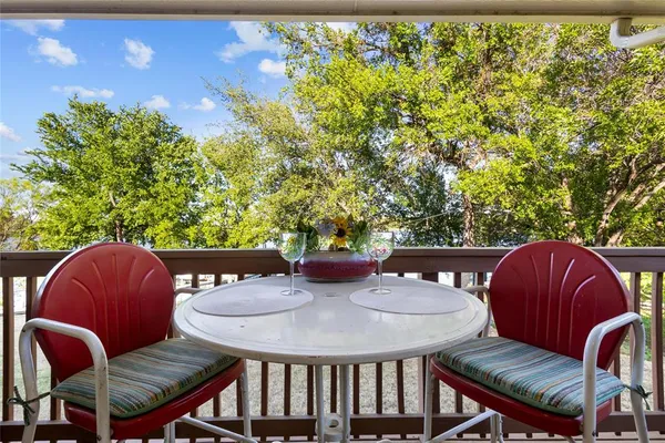 a view of a patio with couches chairs potted plants and floor to ceiling window with wooden floor