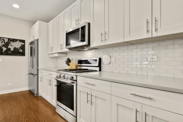 1027 Walnut Way Oak Park, IL 60302 - Photo 13 of 35 a kitchen with stainless steel appliances granite countertop white cabinets a sink a stove a refrigerator and white cabinets