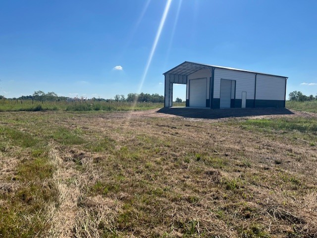 22099 Sattler Road Winnie, TX 77665 - Photo 14 of 23 30x45 metal building features a 15-ft. overhang and sits on a 30x60 concrete slab foundation, with three 12x14 roll-up doors for easy equipment or vehicle access