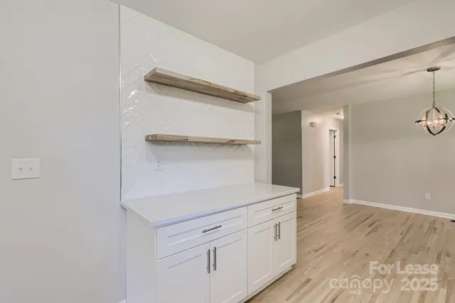 a kitchen with white cabinets and a wooden floor