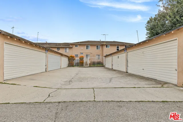 a view of a white house with a large tree and wooden fence