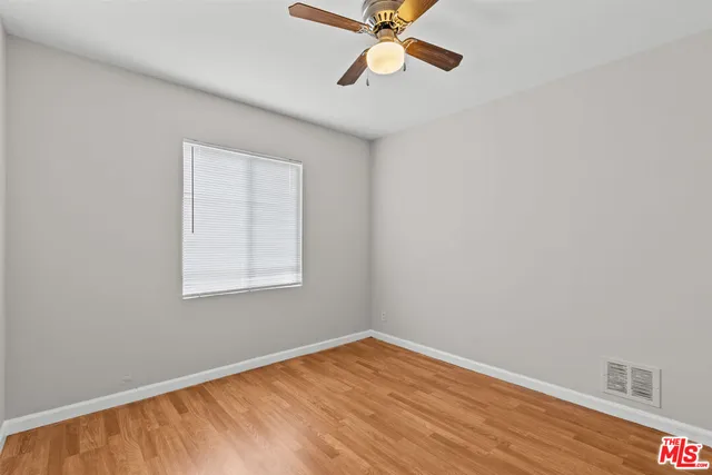 an empty room with wooden floor fan and windows