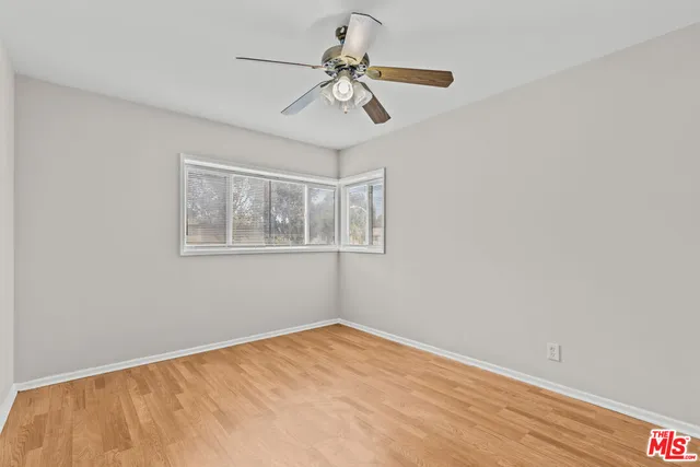 a view of empty room with wooden floor and fan