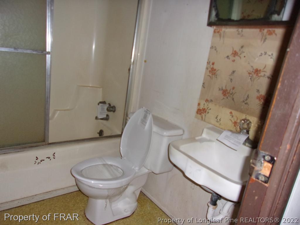 1877 H B Lewis Road Clinton, NC 28328 - Photo 7 of 10 a white toilet sitting next to a bathroom sink and a mirror