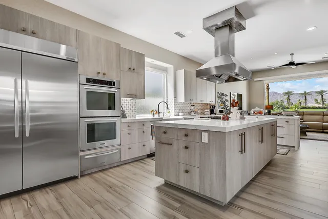 a kitchen with stainless steel appliances kitchen island granite countertop a stove a sink and a refrigerator