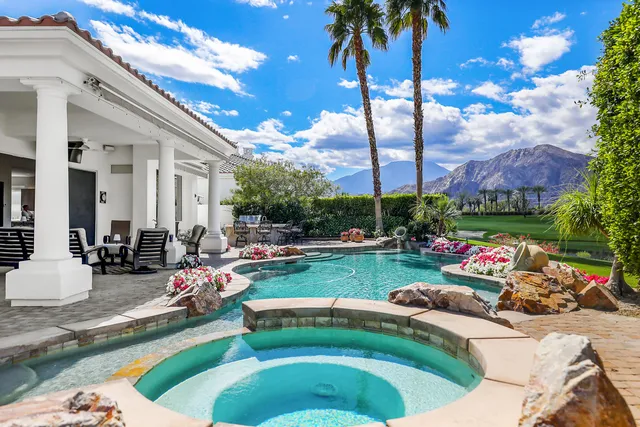 a view of a backyard with couches table and chairs and potted plants