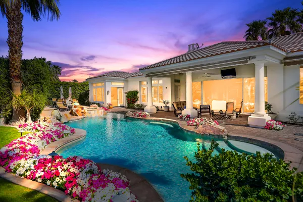 a view of a house with swimming pool lawn chairs and a yard