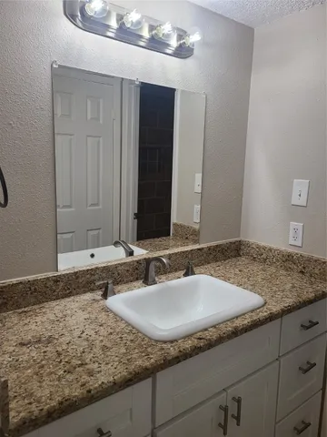 a bathroom with a granite countertop sink and a mirror