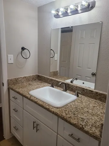 a bathroom with a granite countertop sink and a mirror
