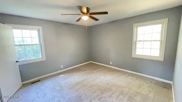 an empty room with a window and a fan