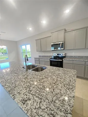 a kitchen with kitchen island granite countertop a stove sink and cabinets