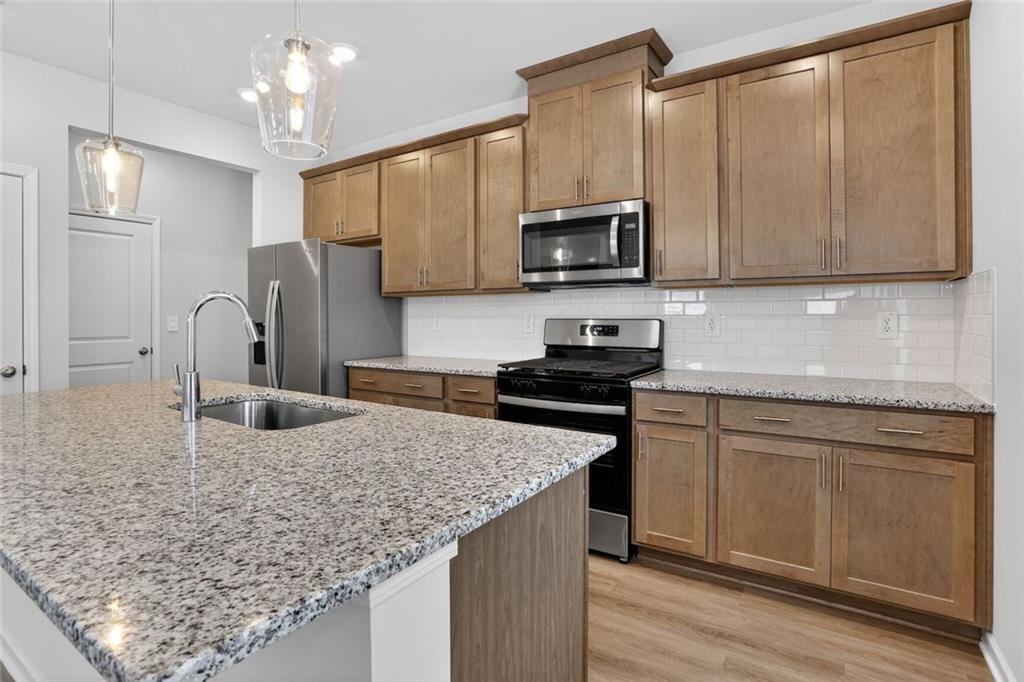 6929 Winchester Place Fairburn, GA 30213 - Photo 17 of 35 a kitchen with stainless steel appliances granite countertop a sink refrigerator and microwave