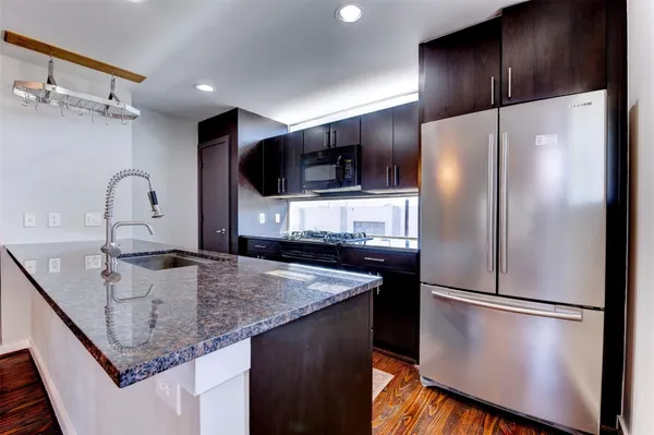 a kitchen with stainless steel appliances granite countertop a refrigerator a stove and a sink with wooden floor